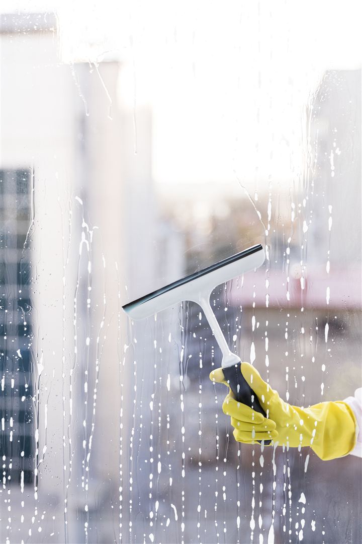 Professional window cleaner working on commercial glass
